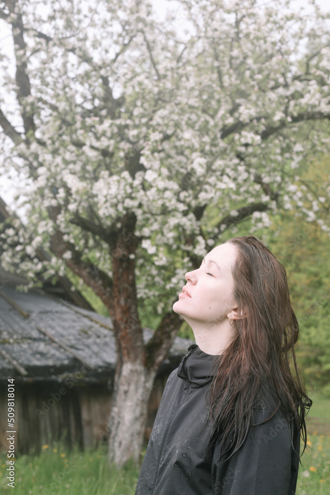 emotional portrait of a young woman standing alone under rain outdoors in spring. emotional portrait of a young woman standing alone under rain outdoors in spring.