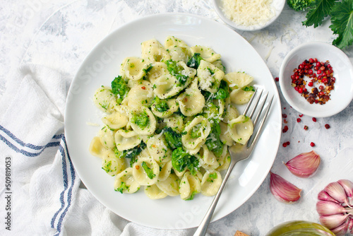 Italian pasta - orecchiette with turnip greens on light background. Mediterranean diet. Top view.