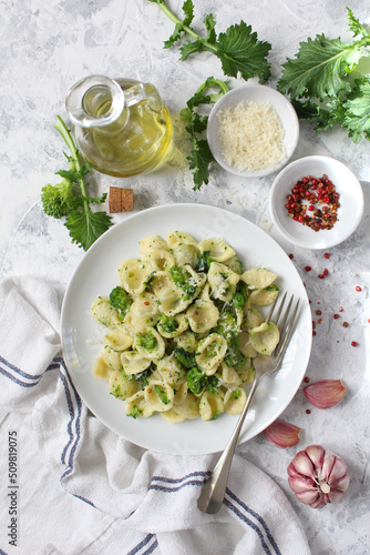 Italian pasta - orecchiette with turnip greens on light background. Mediterranean diet. Top view. photo
