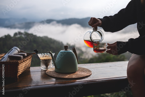 Closeup of a woman making drip coffee to drink with a beautiful mountain and nature view in background