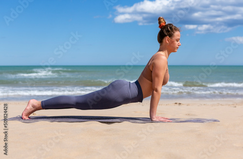 woman doing pilates on the shore of the beach in sportswear
