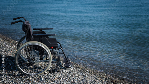 Foto An empty wheelchair on a rocky seashore.