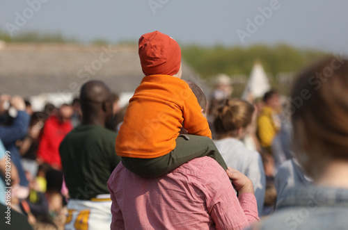 Child on the shoulders of a man. View from the back of the head
