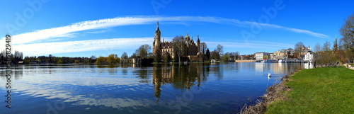 weites Panorama vom Schweriner Schloss im See mit grüner Wiese und weißen Wolken am blauen Himmel