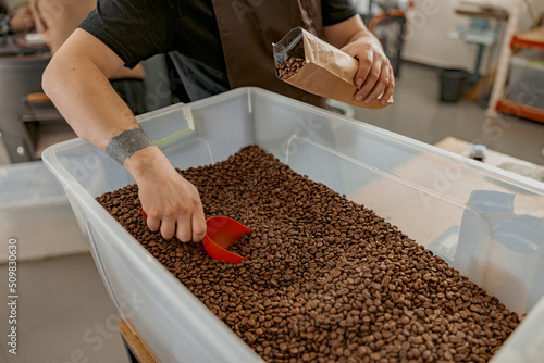 Close up of barista's hands packing roasted coffee beans into packages for sale 