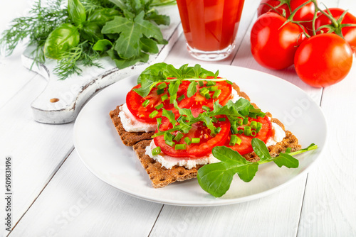Crispbread with curd cheese, tomatoes, green onions, arugula and basilica. Delicious and healthy breakfast