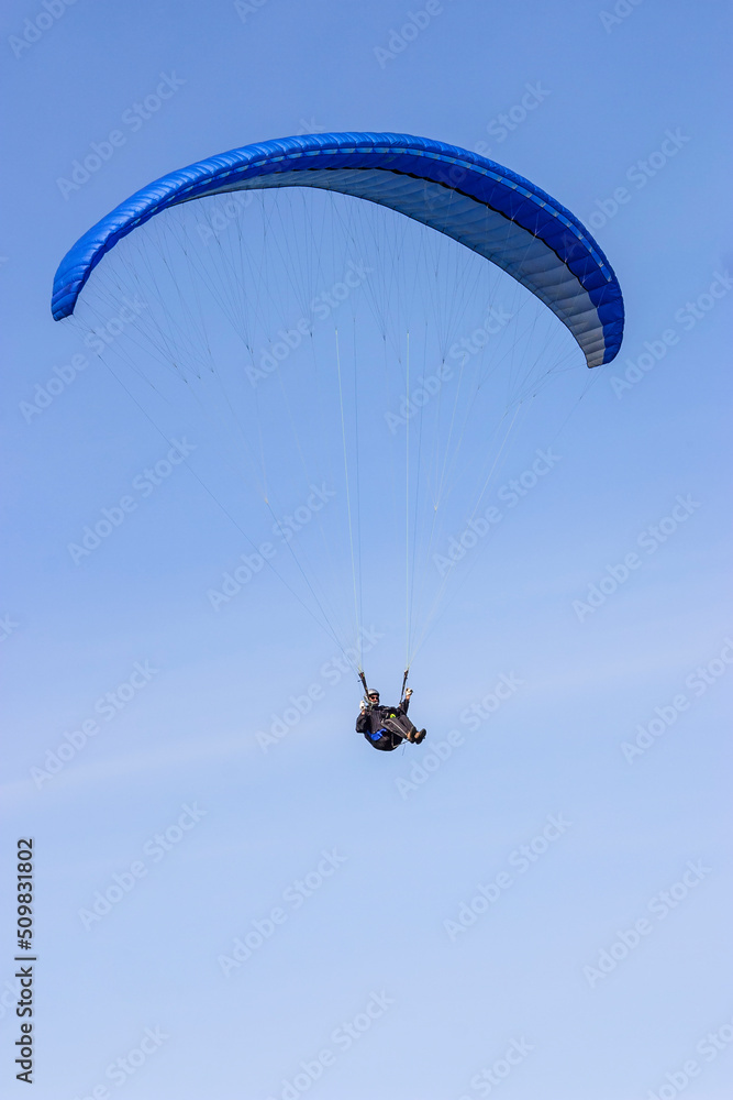 One paraglider flies in the clear sky