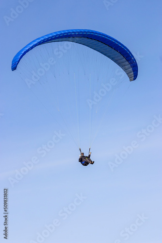 One paraglider flies in the clear sky