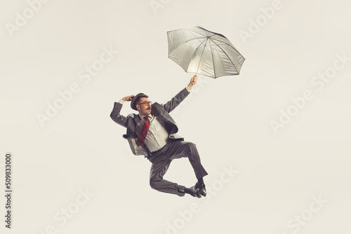 Portrait of young man dressed in 50s, 60s style with umbrella isolated on white background. Concept of culture, art, wellbeing, beauty and ad.