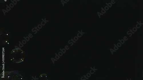 Soap bubbles falling through dark background. Abstract.