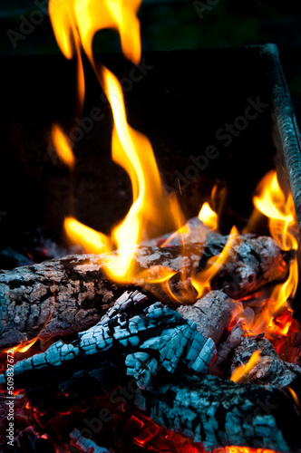 Flame of burning fire wood and smoldering charcoal close view abstract background