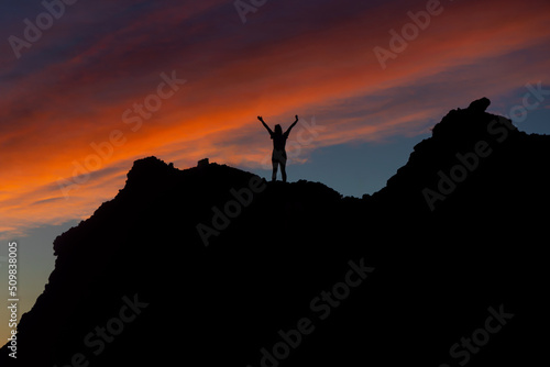 Silhouette of the girl on top of the rocks. Beautiful colorful sunset sky. Punta de Teno, near Buenavista del Norte, Santa Cruz de Tenerife.