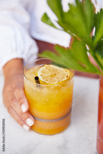Cocktail de naranja en restaurante. Mujer sujetando vaso con la mano.