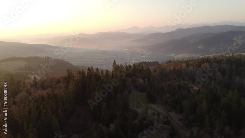 Sunrise over the Slovak countryside with a view near the town of Zborov nad Bystrica. Stone tower on the valley of Oravská magura. Morning orange soft light. Drone shot photo