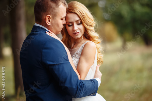 The bride and groom walk together in the park. Happy wedding couple enjoy each other. Wedding day. Marriage.