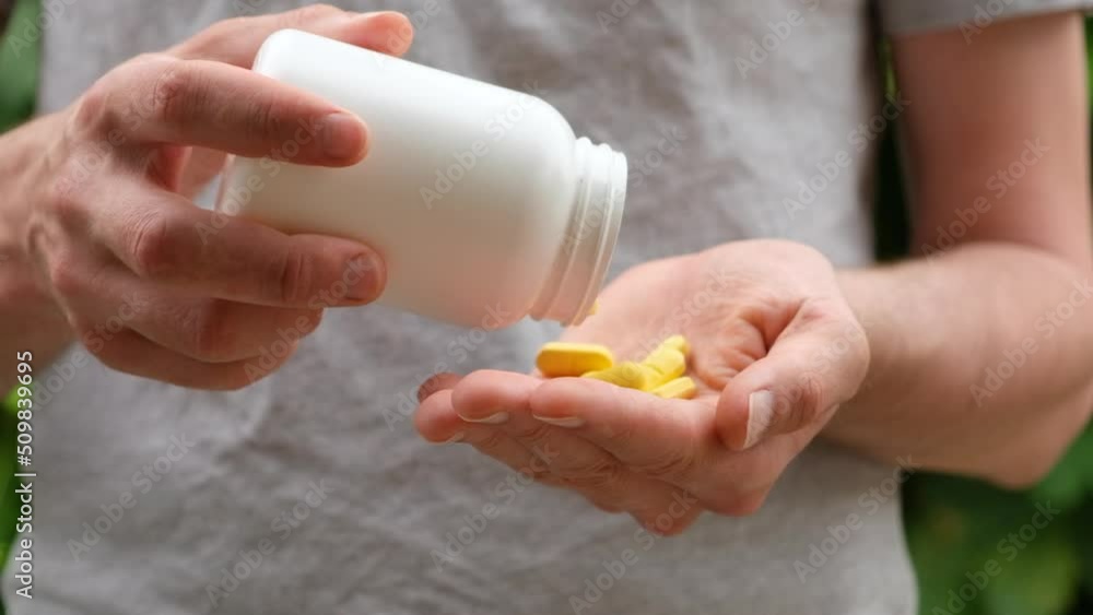 Close up shot of a man pouring yellow pills from white plastic bottle into hand. Slow motion. Close up shot of a man pouring yellow pills from white plastic bottle into hand. Slow motion.