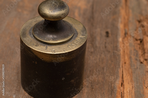 Antique brass scale weight on rustic wood texture, labeled Libra 1/4