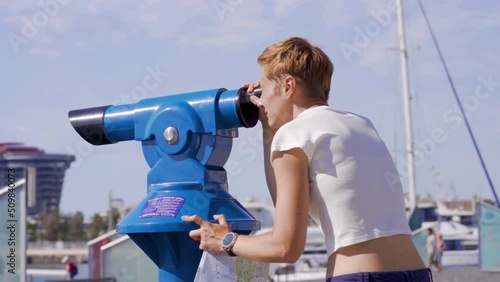 Woman use binoscope in the Barcelona port. Blue city binocular, telescope for town view photo