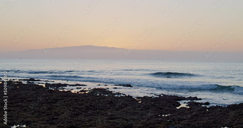 Ocean Waves Crashing on volcanic stones at sunset. Colorful sunset view over the island of La Gomera. Ocean Waves Crashing on volcanic stones at sunset. Colorful sunset view over the island of La Gomera.