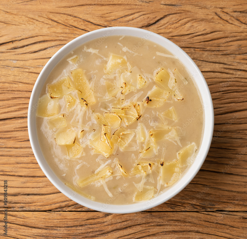 Onion soup with cheese in a bowl over wooden table Onion soup with cheese in a bowl over wooden table