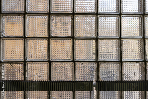 Textured glass wall made of rectangular blocks with traces of mechanical wear
