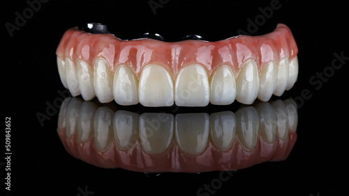 beautiful upper jaw prosthesis made of zircon with a pink artificial gum on black glass with reflection