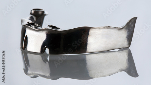 creative photo of dental beams made of pure titanium to create a prosthesis on a white background with reflection