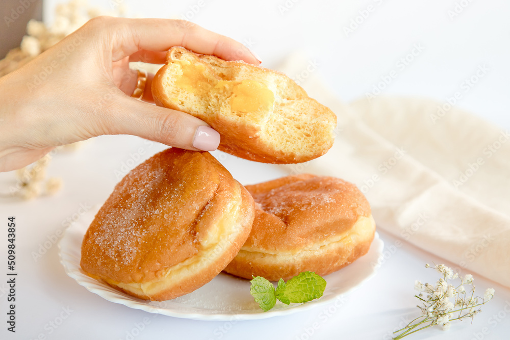 Bolas de Berlim, Berliner or donuts filled with egg jam, a very popular dessert in Portuguese pastry shops. Person tasting a berlin ball.
