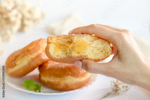 Bolas de Berlim, Berliner or donuts filled with egg jam, a very popular dessert in Portuguese pastry shops. Person tasting a berlin ball. photo