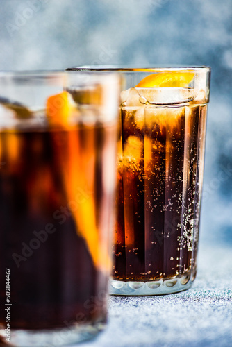 Close-up of two cola drinks with ice cubes and slices of fresh orange