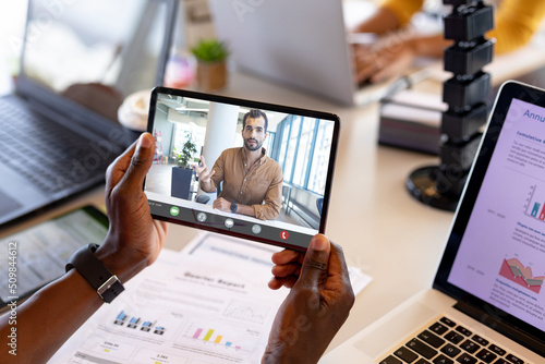 Cropped hands of african ameircan businessman with digital tablet during video call with colleague