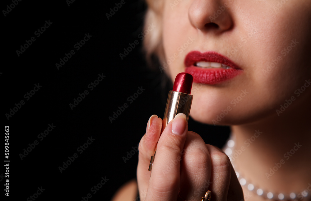 young woman paints her lips with lipstick