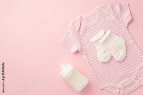Baby accessories concept. Top view photo of pink bodysuit socks and bottle on isolated pastel pink background with copyspace