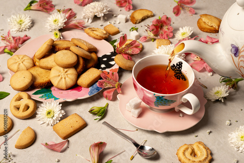 Butterfly pink tea cup and saucer with assorted butter cookies platter and flowers with teapot