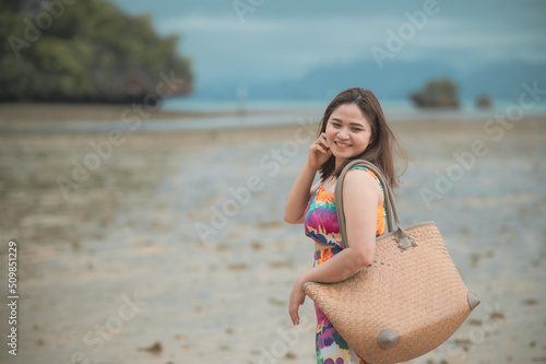 Baeautiful asian woman carrying a bag happy smile by the sea photo