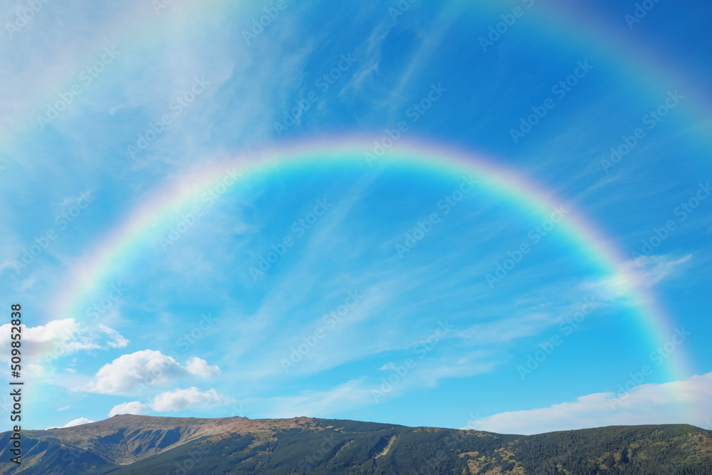 Picturesque mountain landscape and beautiful double rainbow in blue sky Picturesque mountain landscape and beautiful double rainbow in blue sky