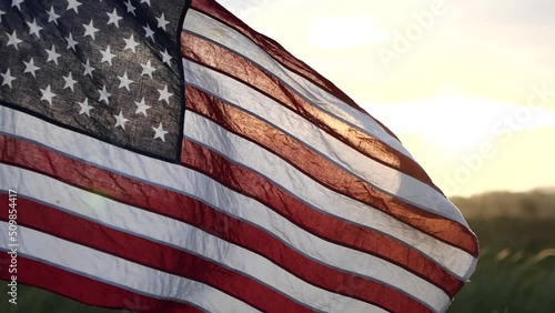 American USA flag waving in the wind against sunset in nature outdoor background. Concept of 4th of July, Memorial Day, Independence Day, Veterans Day, American Celebration, Patriots, Labor, President
