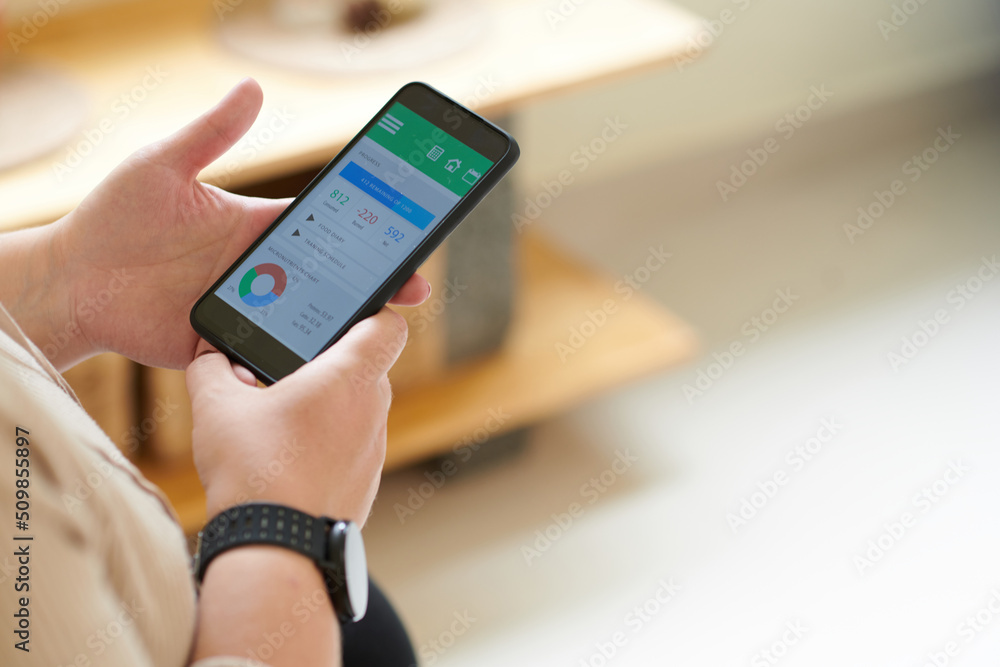 Close-up image of slimming woman monitoring her progress via application on smartphone Close-up image of slimming woman monitoring her progress via application on smartphone