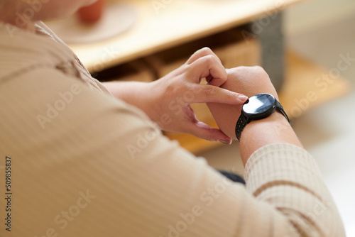 Close-up image of plus size woman controlling her activity via application on smartwatch