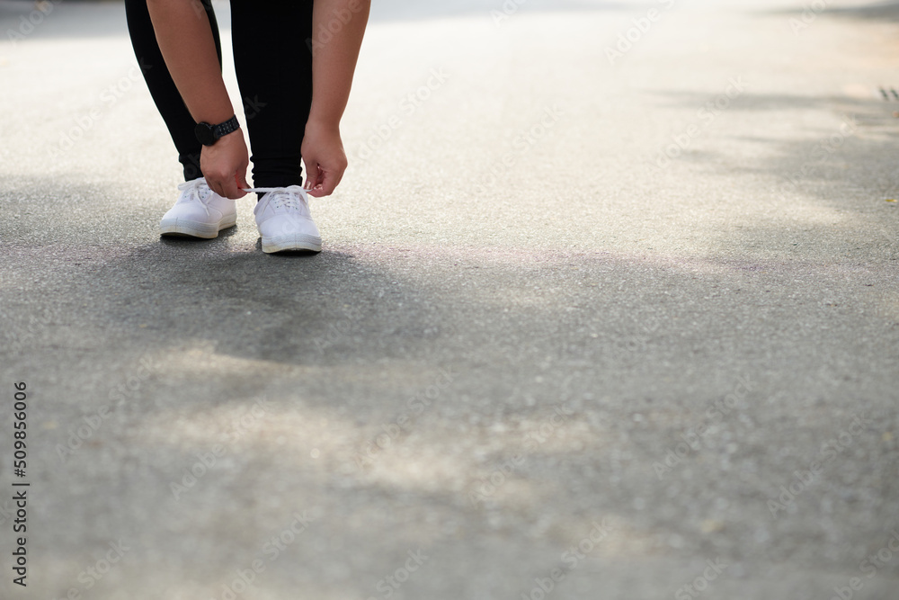 Close-up image of plus size woman tying show laces and getting ready for morning jog Close-up image of plus size woman tying show laces and getting ready for morning jog