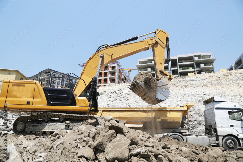 Excavator on earthworks at construction site. Backhoe on foundation work and road construction. Heavy machinery and construction equipment. Excavator under building Excavator on earthworks at construction site. Backhoe on foundation work and road construction. Heavy machinery and construction equipment. Excavator under building