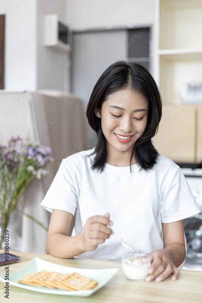 Half-Japanese woman eats yoghurt with cereal for breakfast in room, Healthy food and digestive system maintenance, The most popular and easy to eat breakfast food. Half-Japanese woman eats yoghurt with cereal for breakfast in room, Healthy food and digestive system maintenance, The most popular and easy to eat breakfast food.
