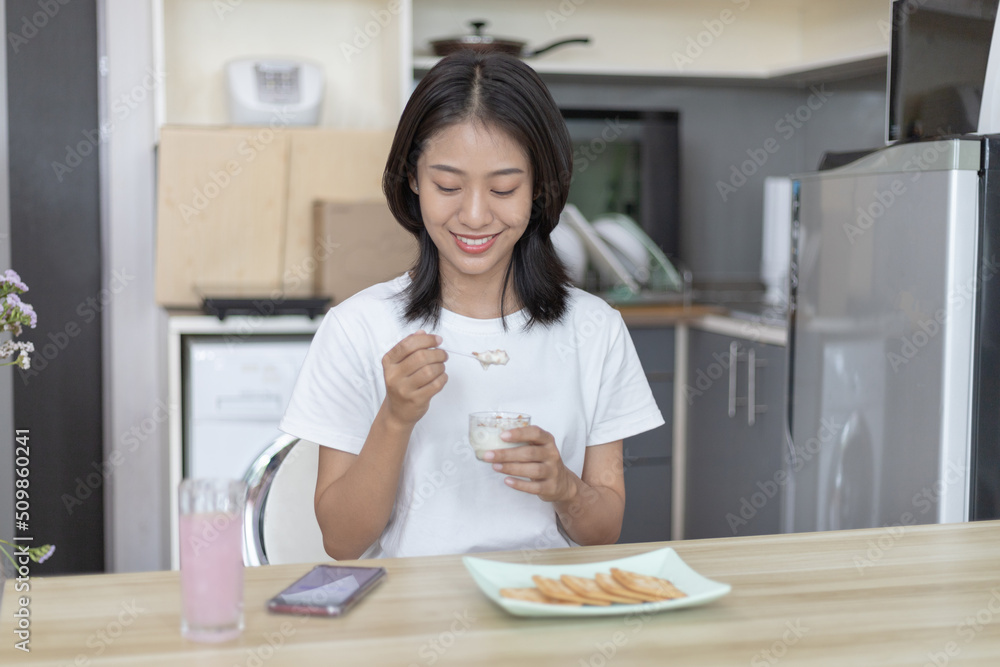 Half-Japanese woman eats yoghurt with cereal for breakfast in room, Healthy food and digestive system maintenance, The most popular and easy to eat breakfast food. Half-Japanese woman eats yoghurt with cereal for breakfast in room, Healthy food and digestive system maintenance, The most popular and easy to eat breakfast food.