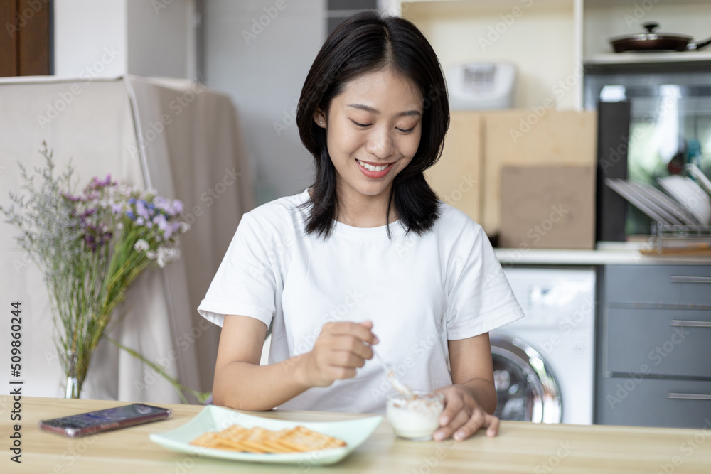 Half-Japanese woman eats yoghurt with cereal for breakfast in room, Healthy food and digestive system maintenance, The most popular and easy to eat breakfast food.
