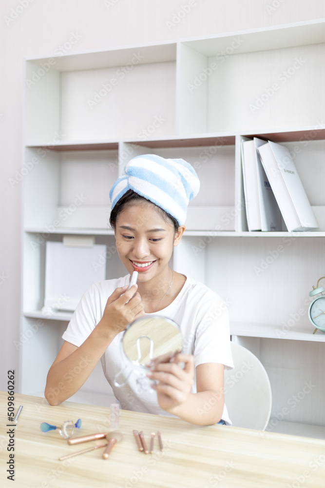 Asian woman putting her hair in a towel and putting on makeup to get ready for work, Make up brush, After taking a shower in the morning, Beautify, Facial care and cosmetics, Make up mirror. Asian woman putting her hair in a towel and putting on makeup to get ready for work, Make up brush, After taking a shower in the morning, Beautify, Facial care and cosmetics, Make up mirror.