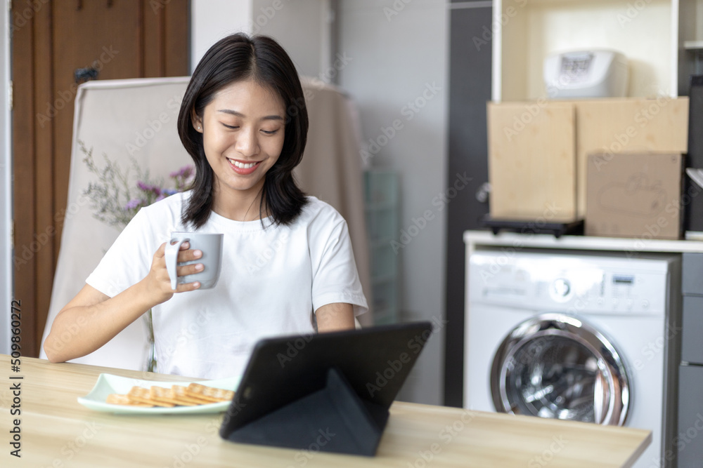 Asian woman eats breakfast with crackers (Healthy whole grain) and juice, Use your phone or tablet to search for morning news, Small room in condominium background, Wake-up activities...