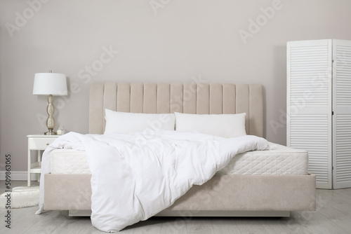 Comfortable bed with soft white mattress, blanket and pillows indoors photo