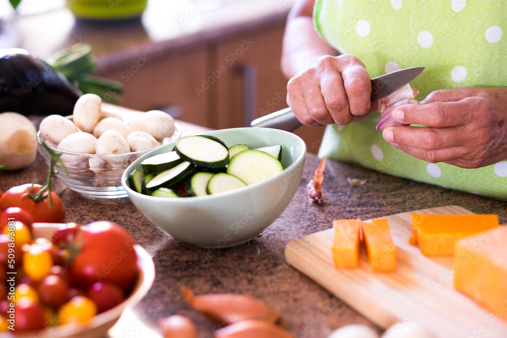 Close up on female hands cutting vegetables in the home kitchen. Fresh raw vegetables on the table Close up on female hands cutting vegetables in the home kitchen. Fresh raw vegetables on the table
