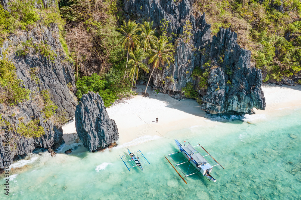 View from above, stunning aerial view of a person on the Entalula Beach, a white sand beach bathed by a crystal clear water. Entalula island, Bacuit Bay, El Nido, Palawan, Philippines.
