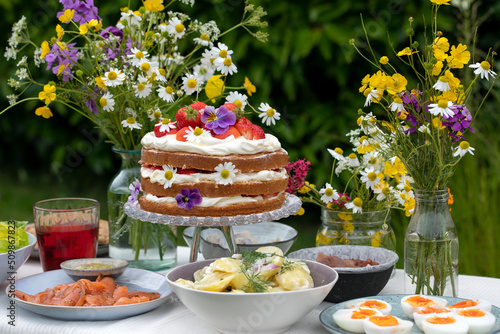 Scandinavian midsummer meal with strawberry and cream cake, potato salad, salmon and eggs
